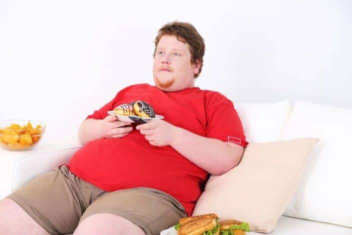 Dicker Mann mit Süßigkeiten auf dem Sofa